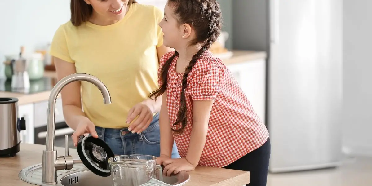 woman and child cleaning a blender in the kitchen