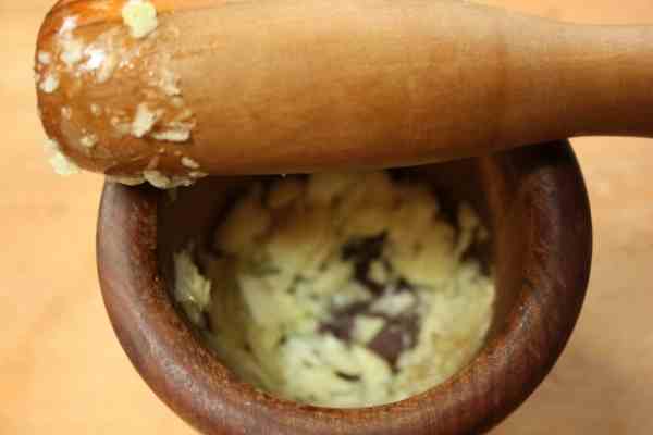 mortar and pestle being used to puree garlic